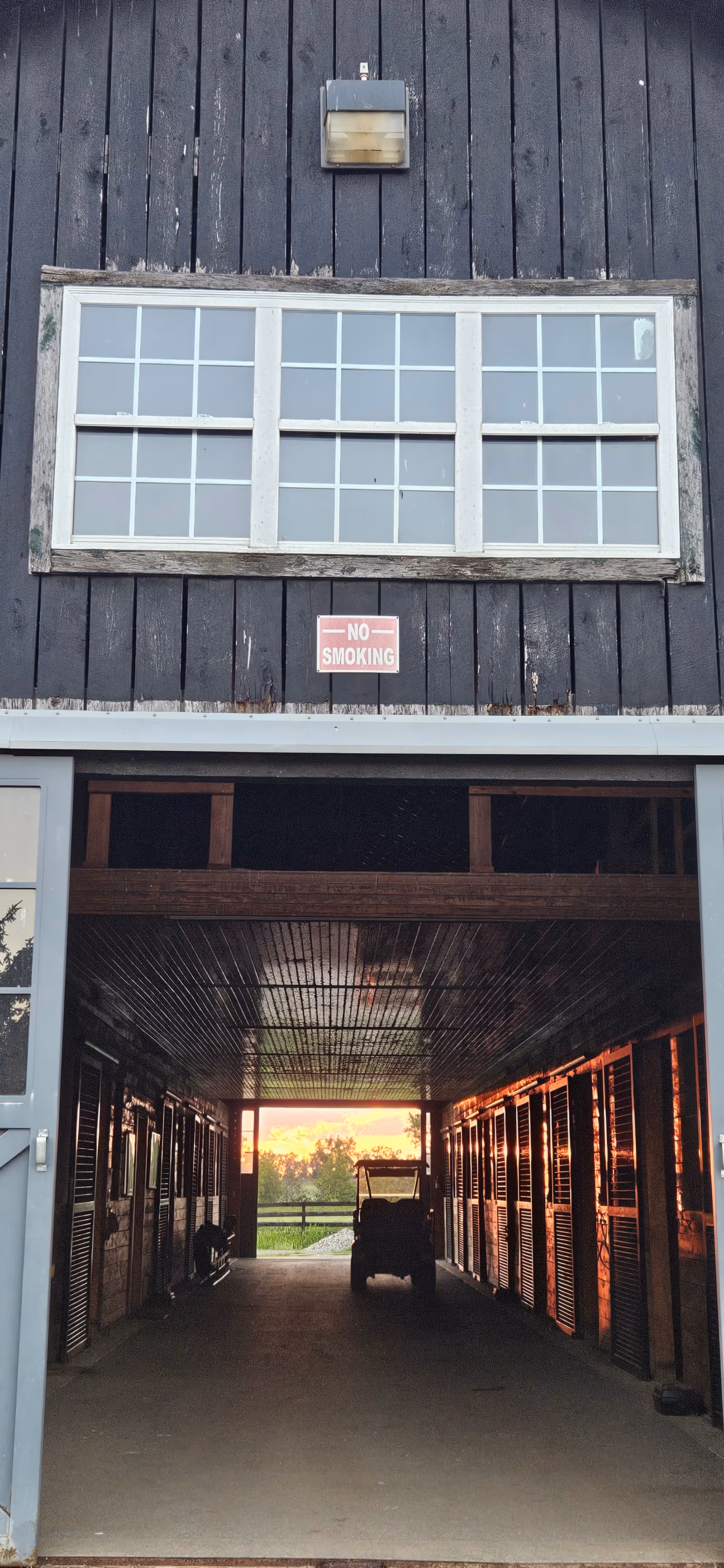 Dark wooden exterior with a large window, no-smoking sign, leading to a dim interior corridor.