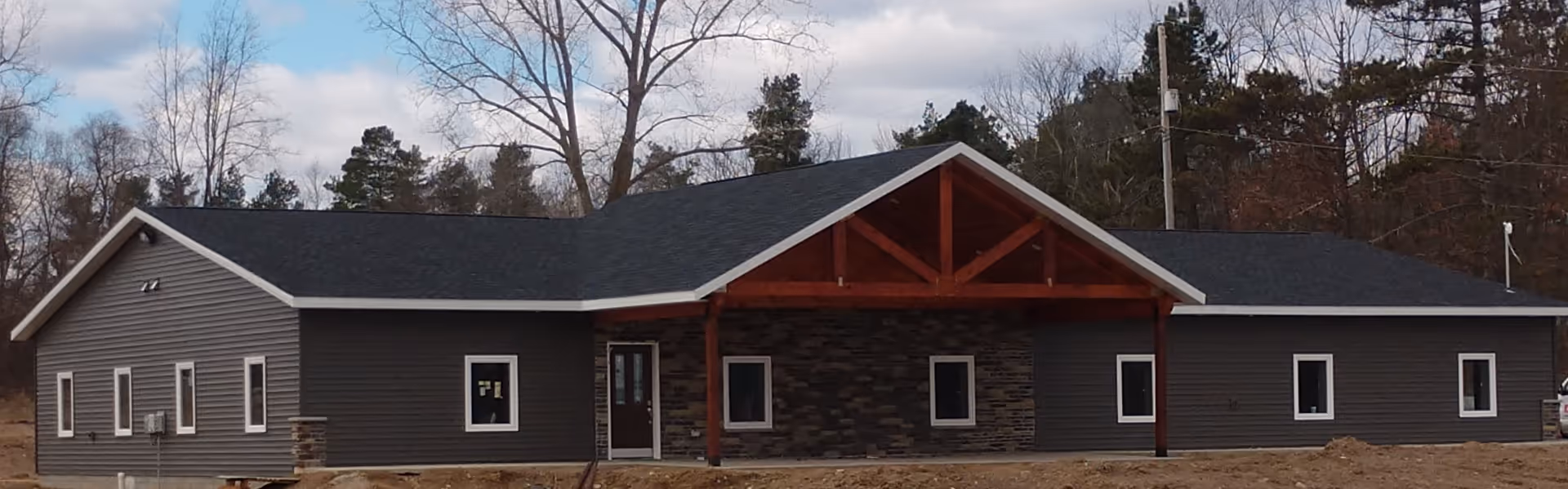 Single-story dark gray facility with stone accents and a covered entrance, no people visible.