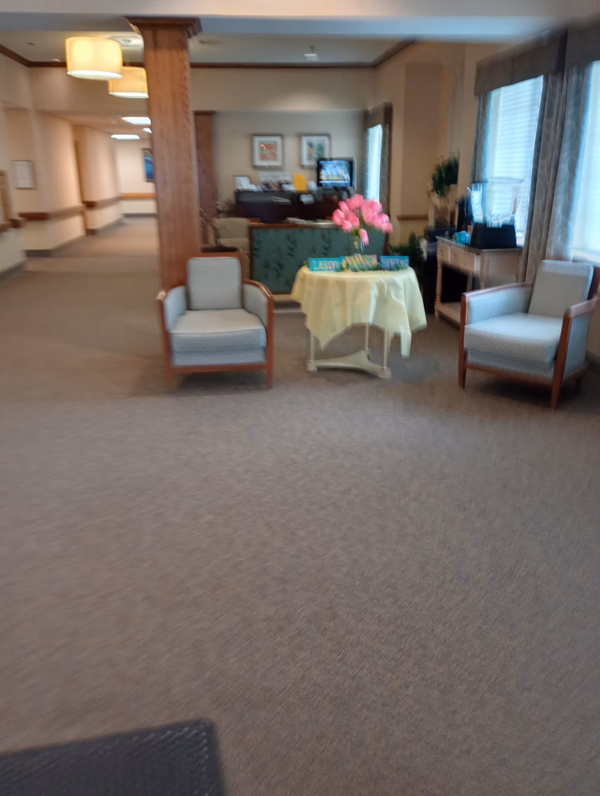 Indoor lounge area with two chairs, a table, and pink flowers.