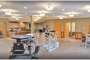 A spacious interior rehab area with exercise equipment and parallel bars in a senior facility.
