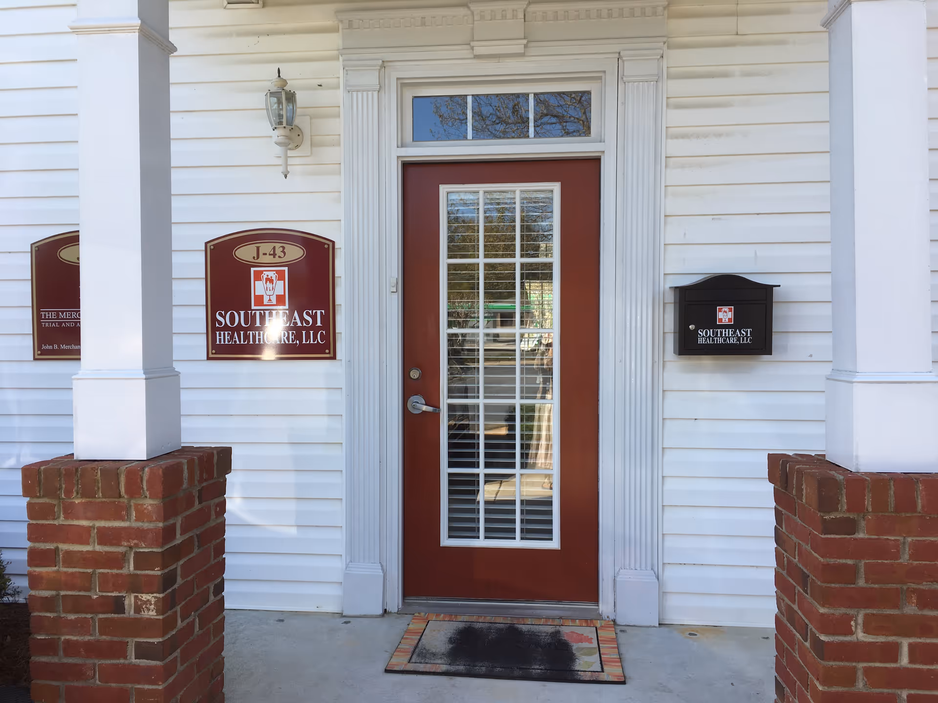 Entrance of a white building with a red door, porch columns, and healthcare signs.