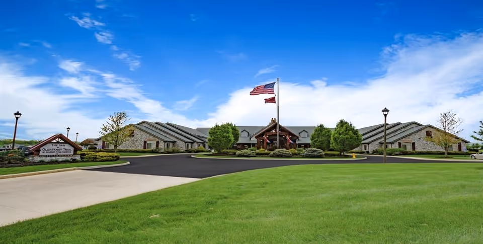 Wide exterior view of The Inn at Olentangy Trail, with flag, entrance, and manicured lawn.
