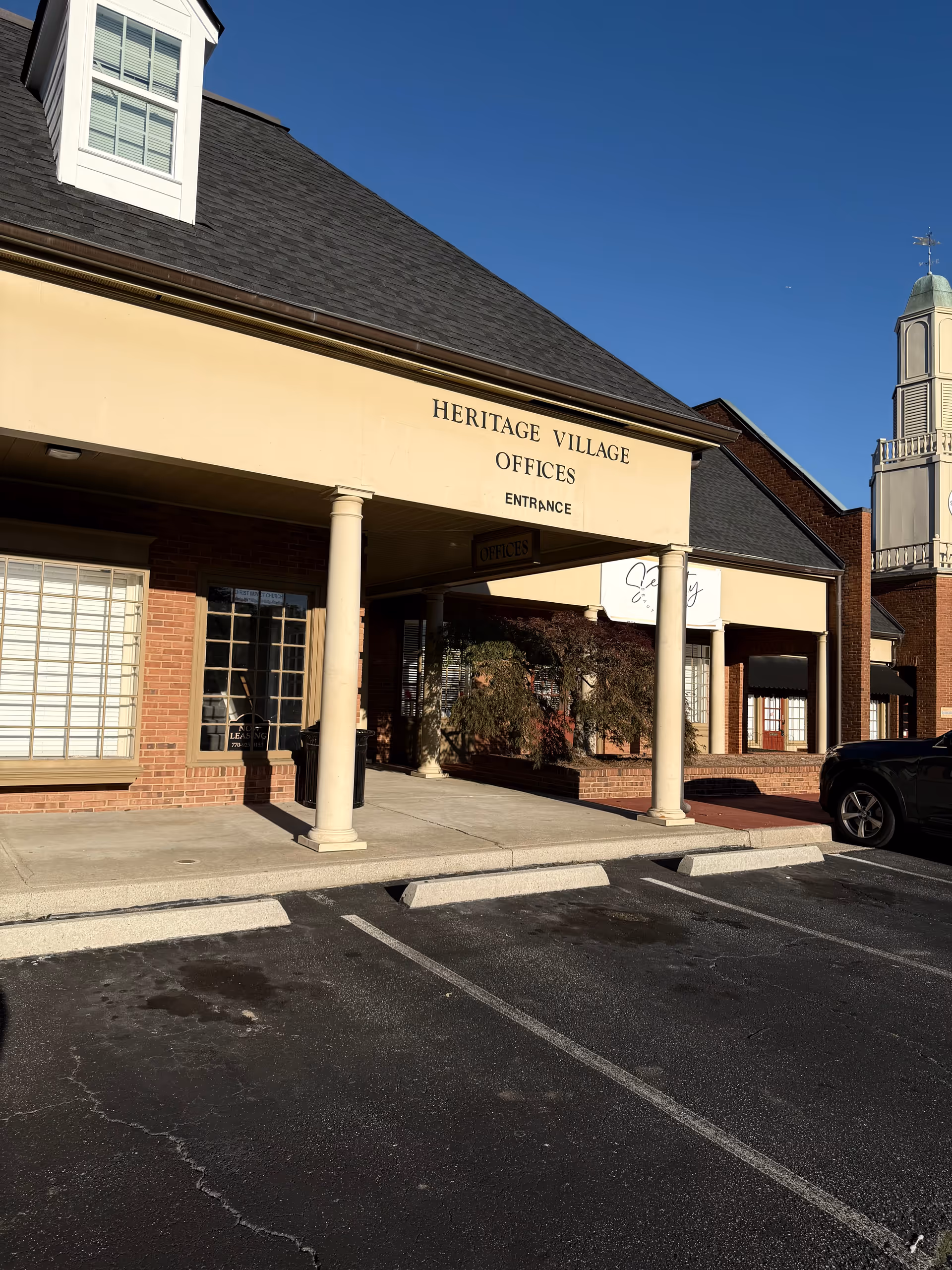 Exterior view of Heritage Village Offices with columns and a parking lot.