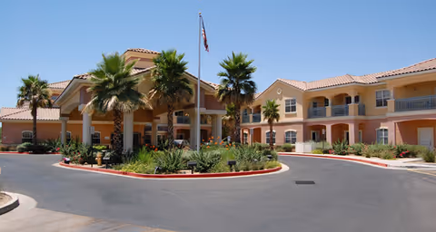 Exterior of Brookdale North Scottsdale with palm trees, circular driveway, and pastel buildings.