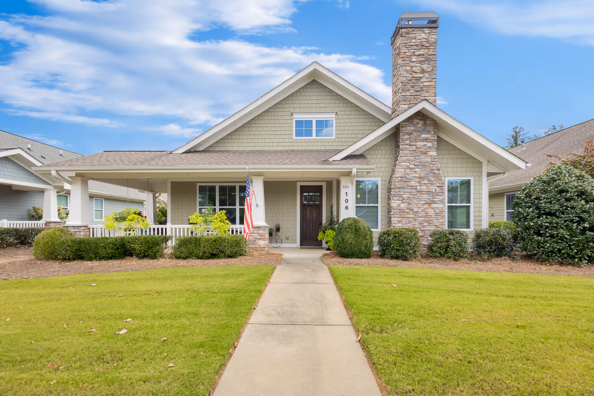 A single-story senior living facility with front entrance, lawn, walkway, and American flag.