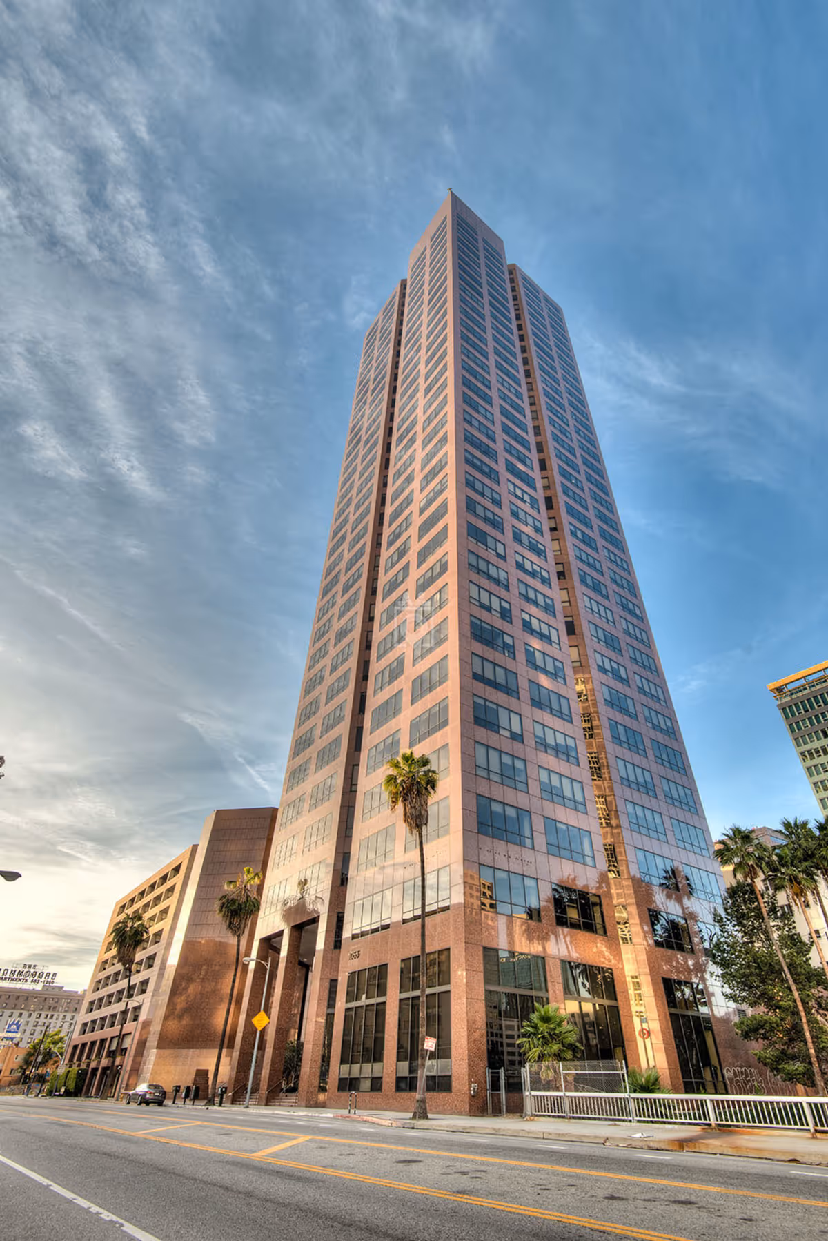 Tall modern high-rise building with glass windows on a city street.