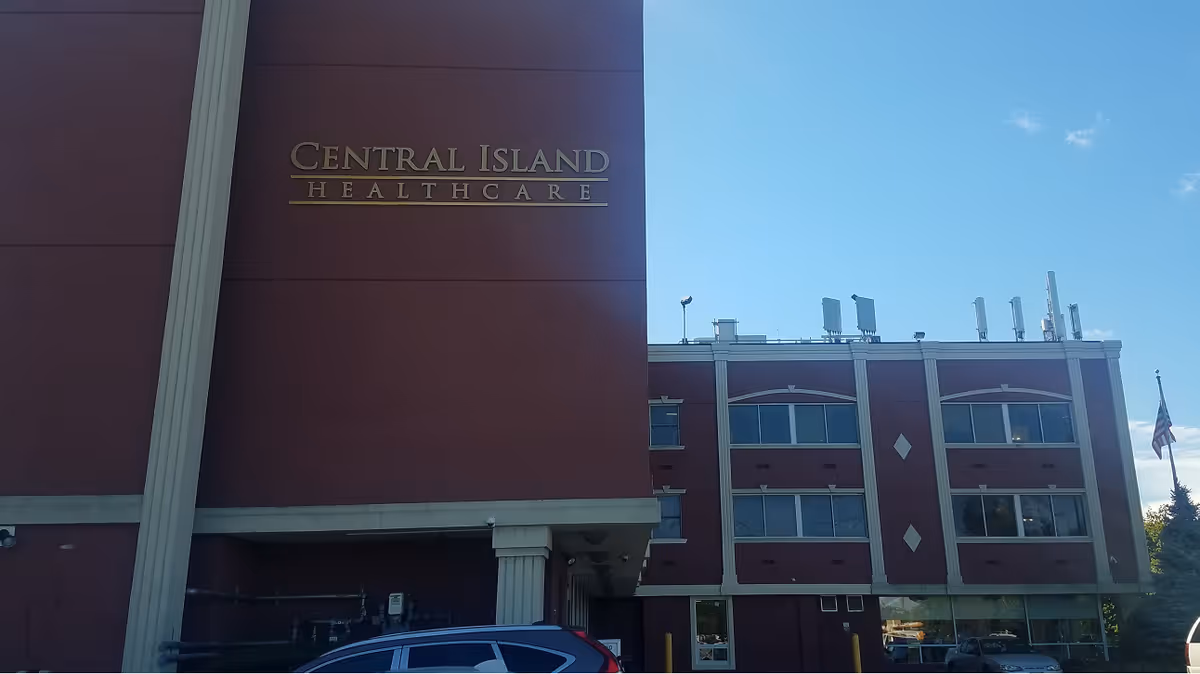 Exterior view of Central Island Healthcare building with maroon facade and clear blue sky.