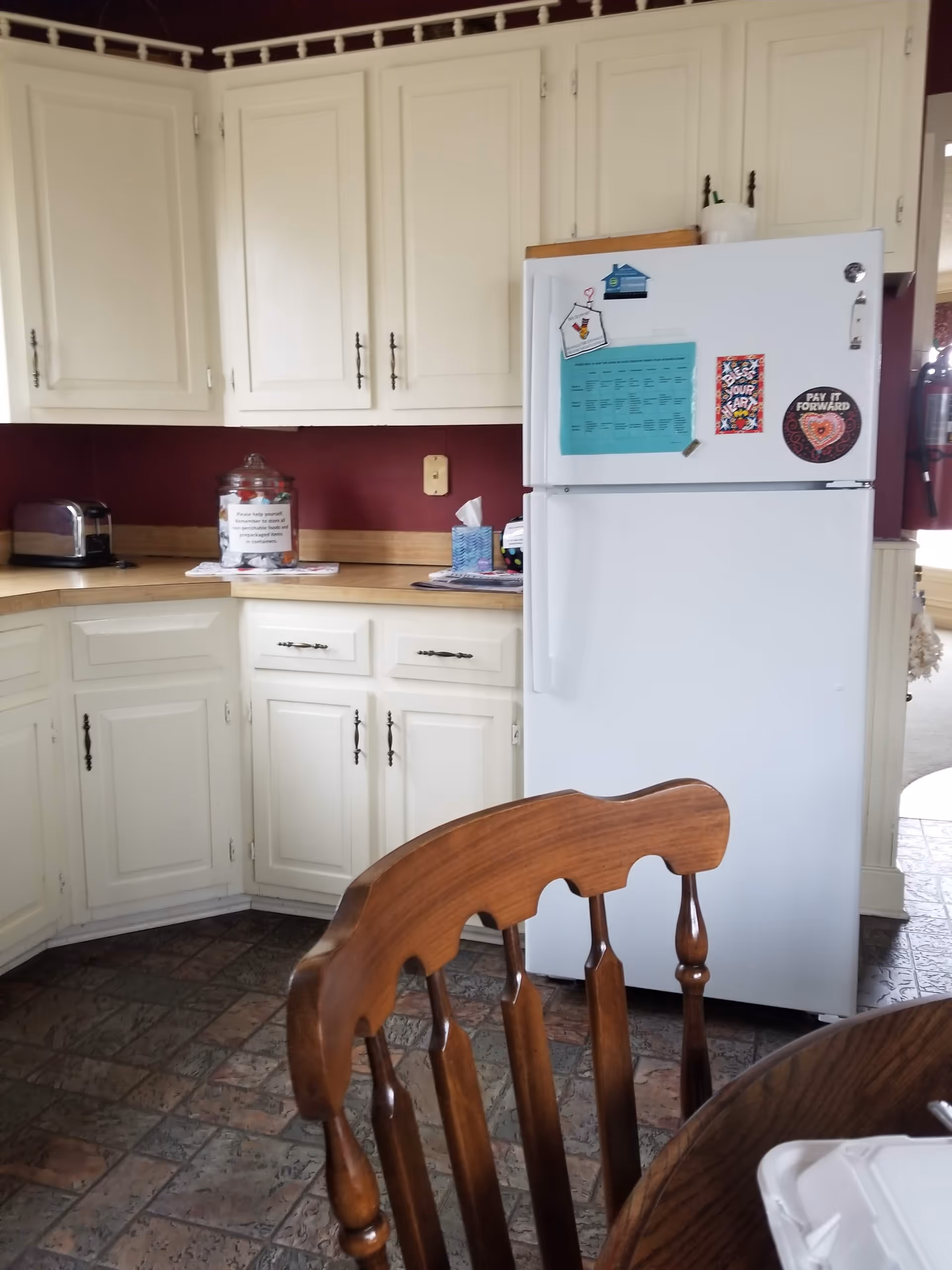 White kitchen with cabinets, refrigerator, and wooden dining table visible.