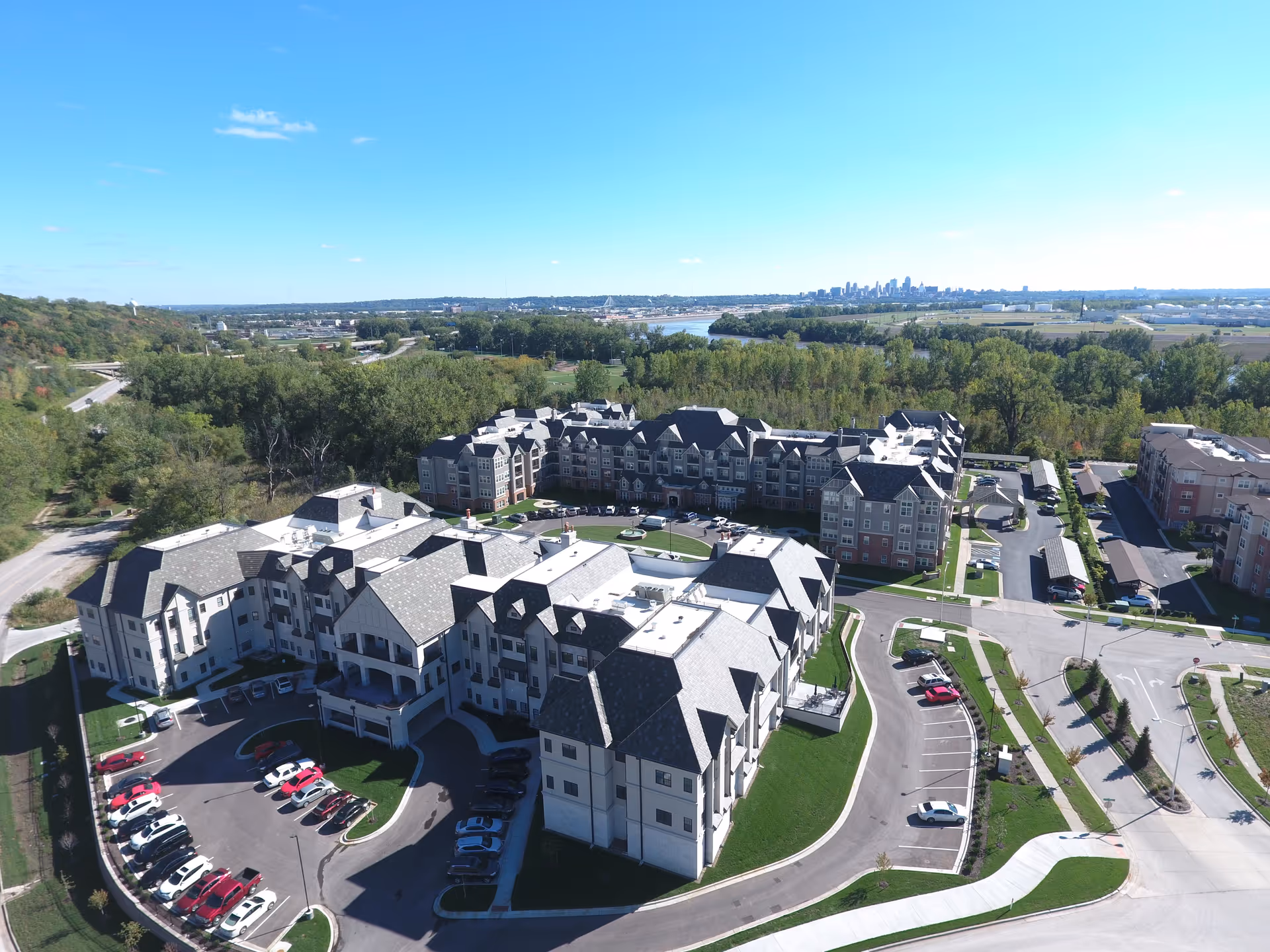 Aerial view of a large senior living campus with gray-roofed buildings and green surroundings.