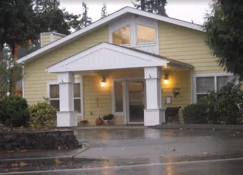 Yellow senior living facility with a covered front porch and warm lanterns at the entrance.
