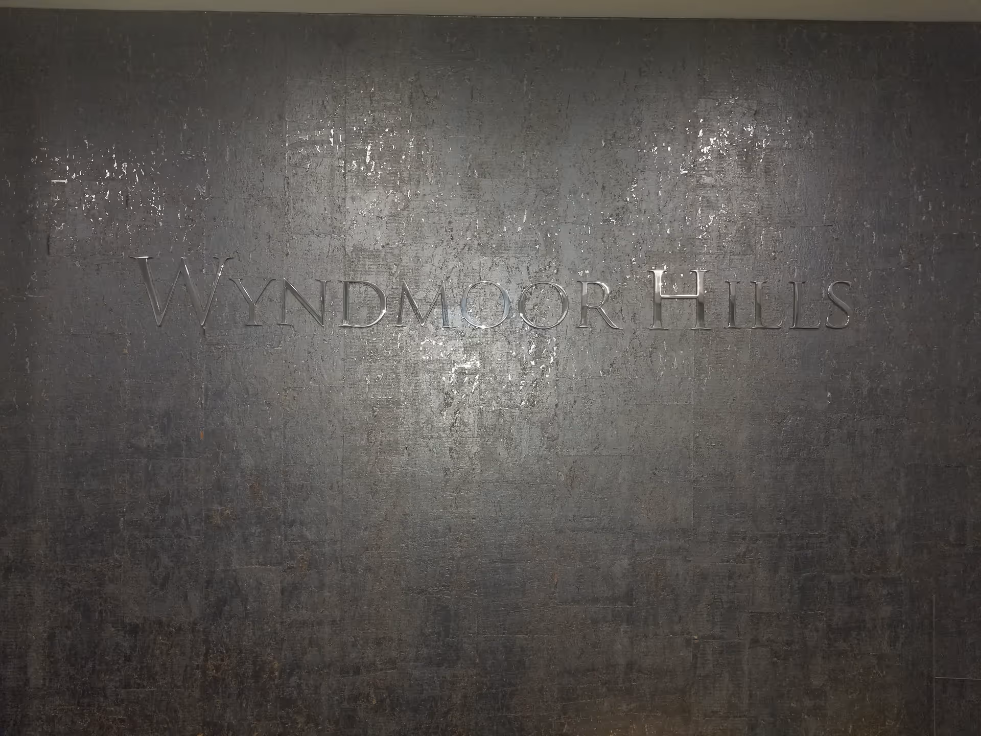 Dark textured wall with embossed WYNDMOOR HILLS signage prominently displayed.