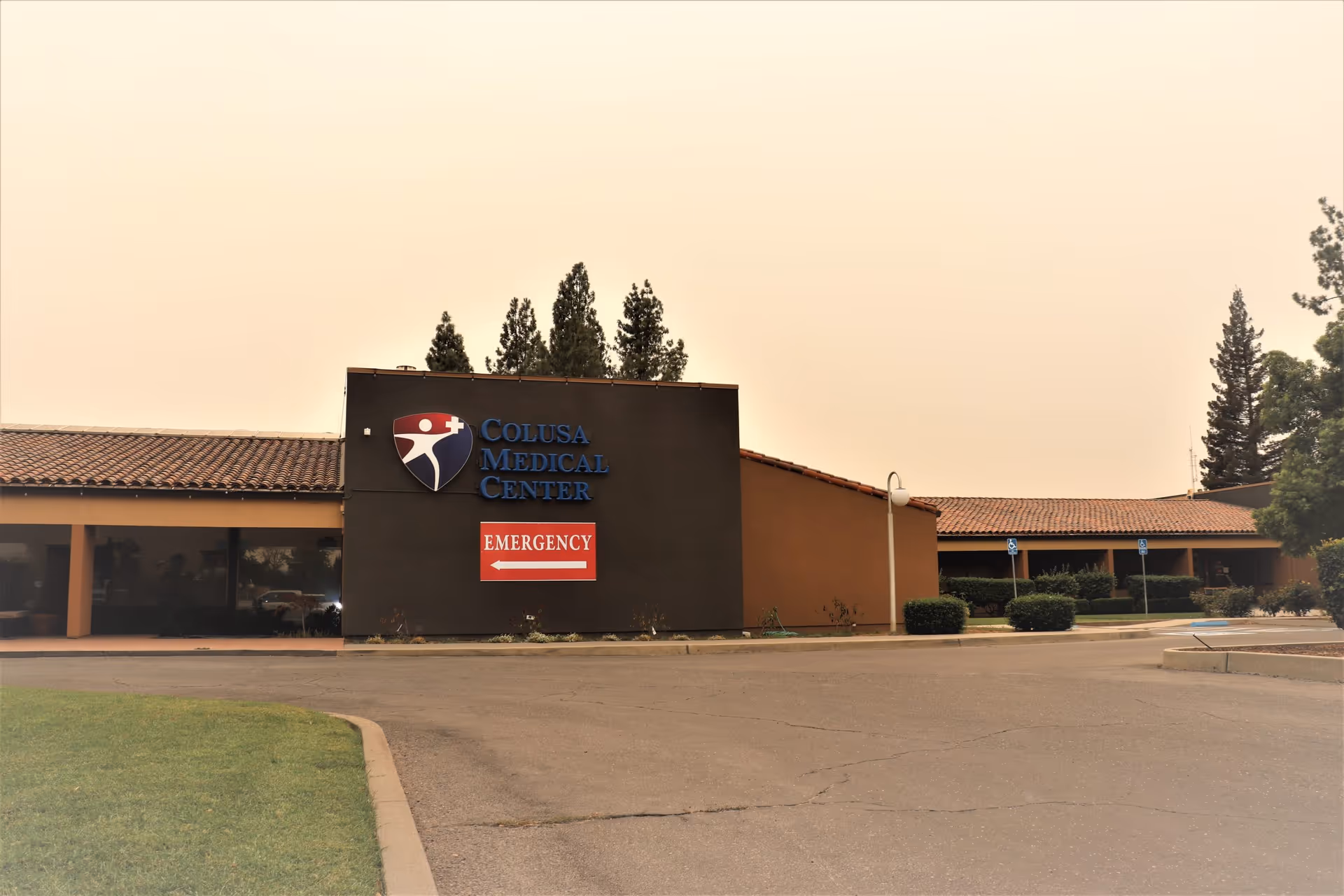 Exterior view of Colusa Medical Center with front sign and emergency entrance in a parking lot.