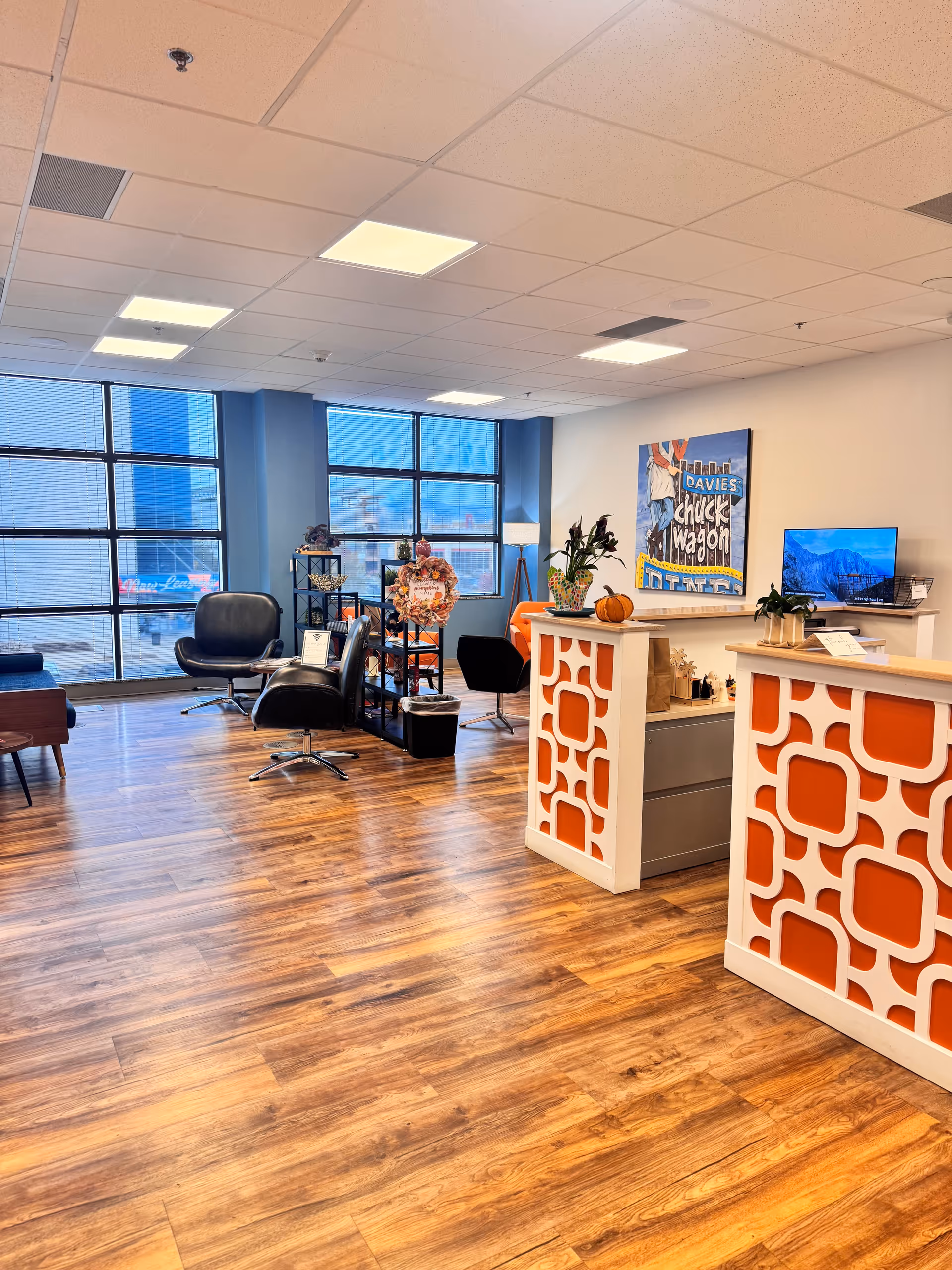 Bright modern lounge lobby with reception desks, seating, plants, artwork, and large windows.