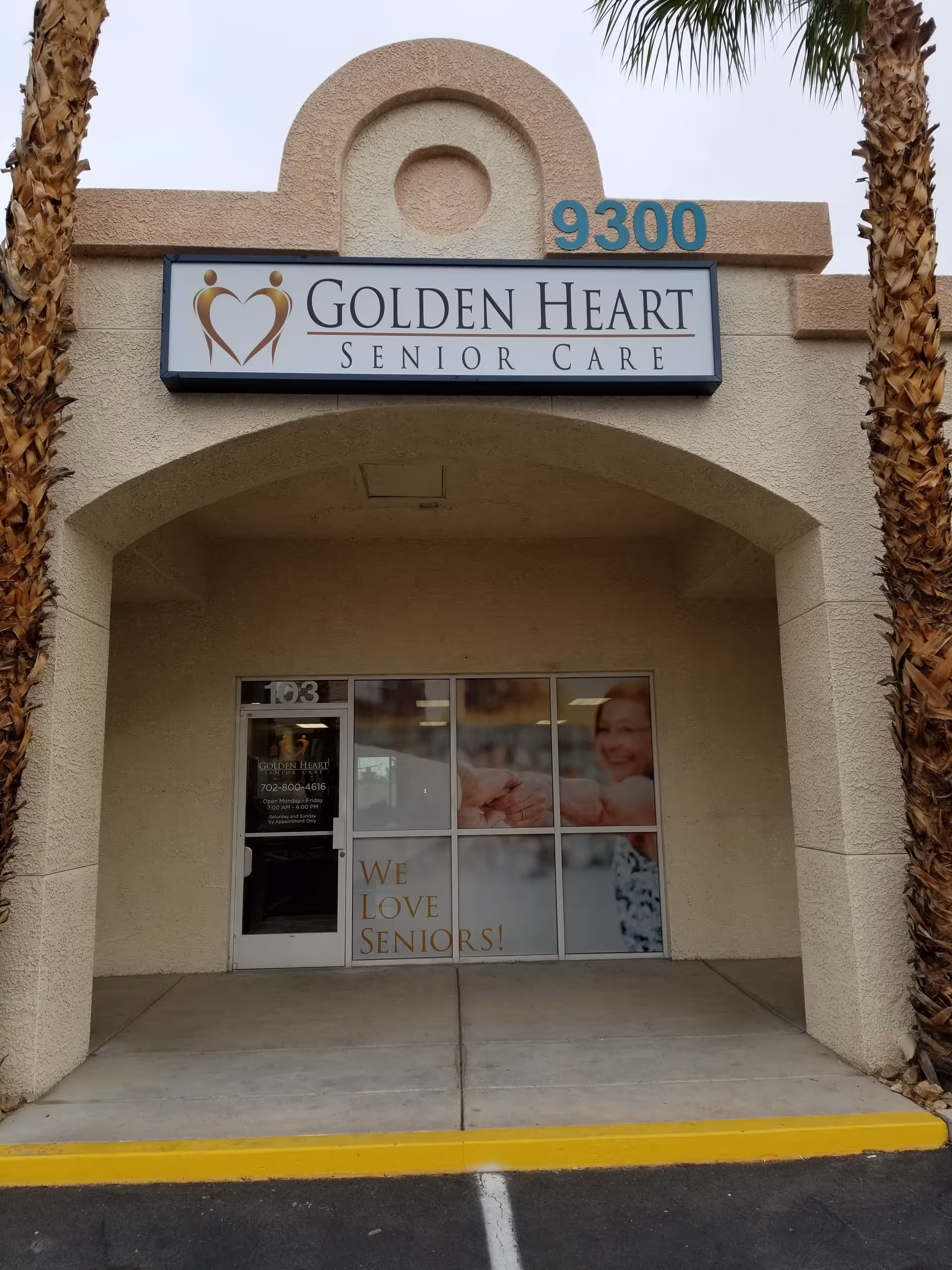 Entrance of Golden Heart Senior Care facility with a sign and glass doors, palm trees nearby.