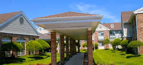 Exterior view of Juniper Village at Spicewood Summit with brick buildings, a covered walkway, and lawn.