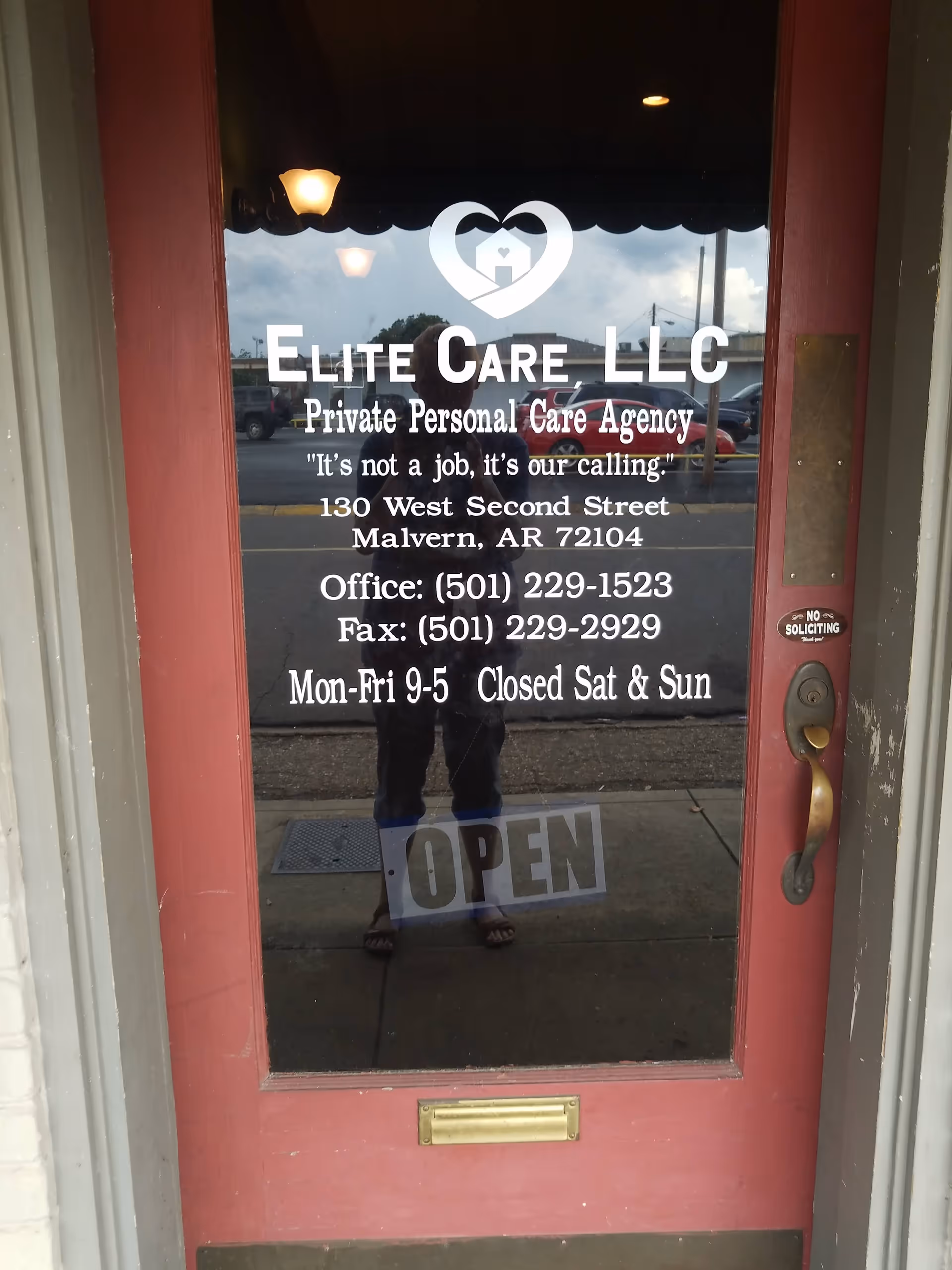 Exterior glass door displaying Elite Care LLC signage with reflected street scene.