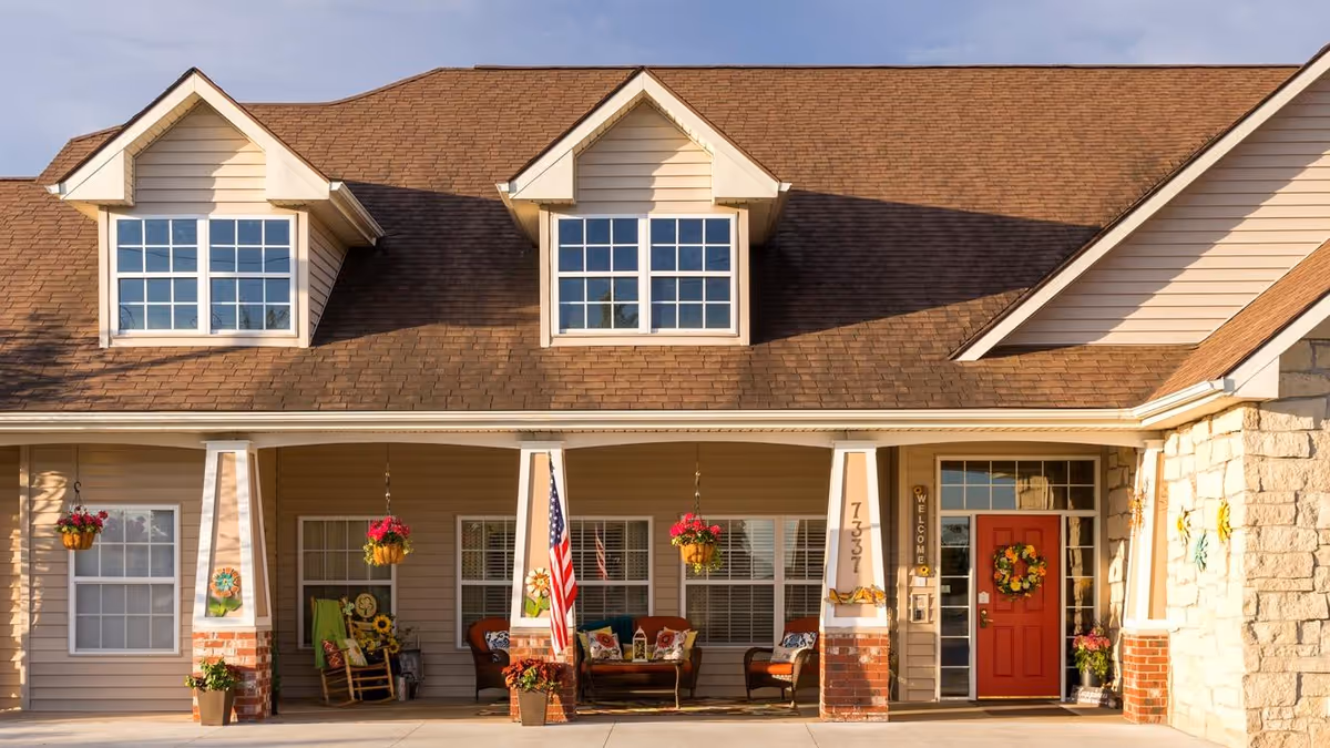 Front exterior of Bickford of Omaha Hickory with porch seating and hanging plants.