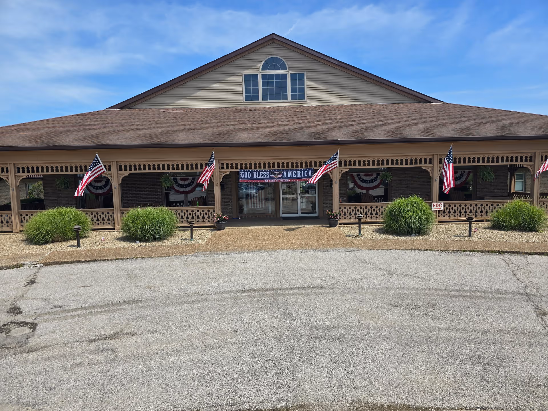 Loogootee Nursing Center exterior: a single-story building with a wide porch and flags.