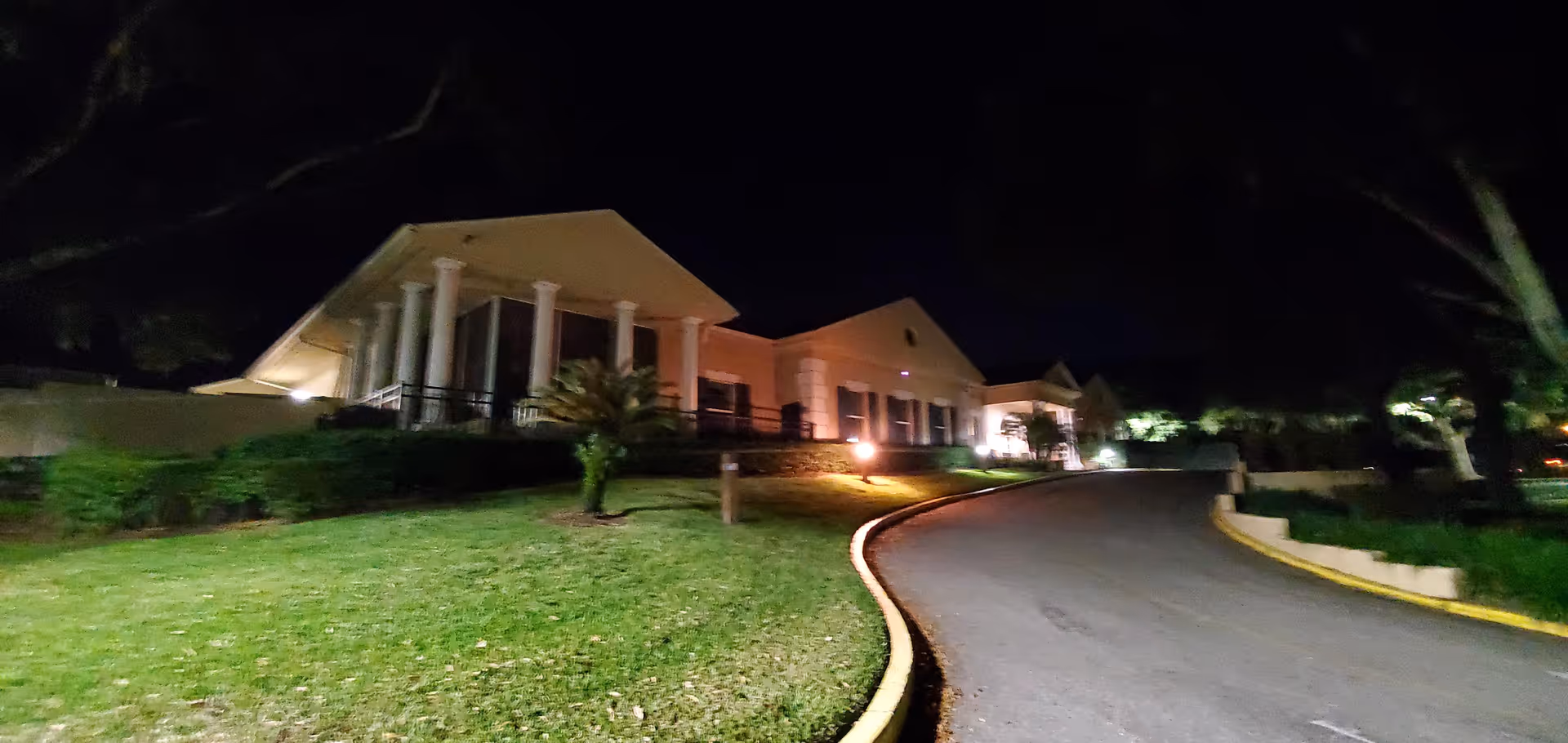 Night exterior of Spring Lake Rehabilitation Center with illuminated entrance and curved driveway.