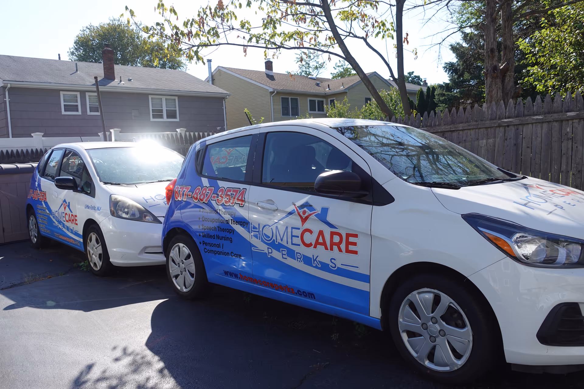 Two branded HomeCare Perks vans parked in a driveway outside a residential neighborhood.