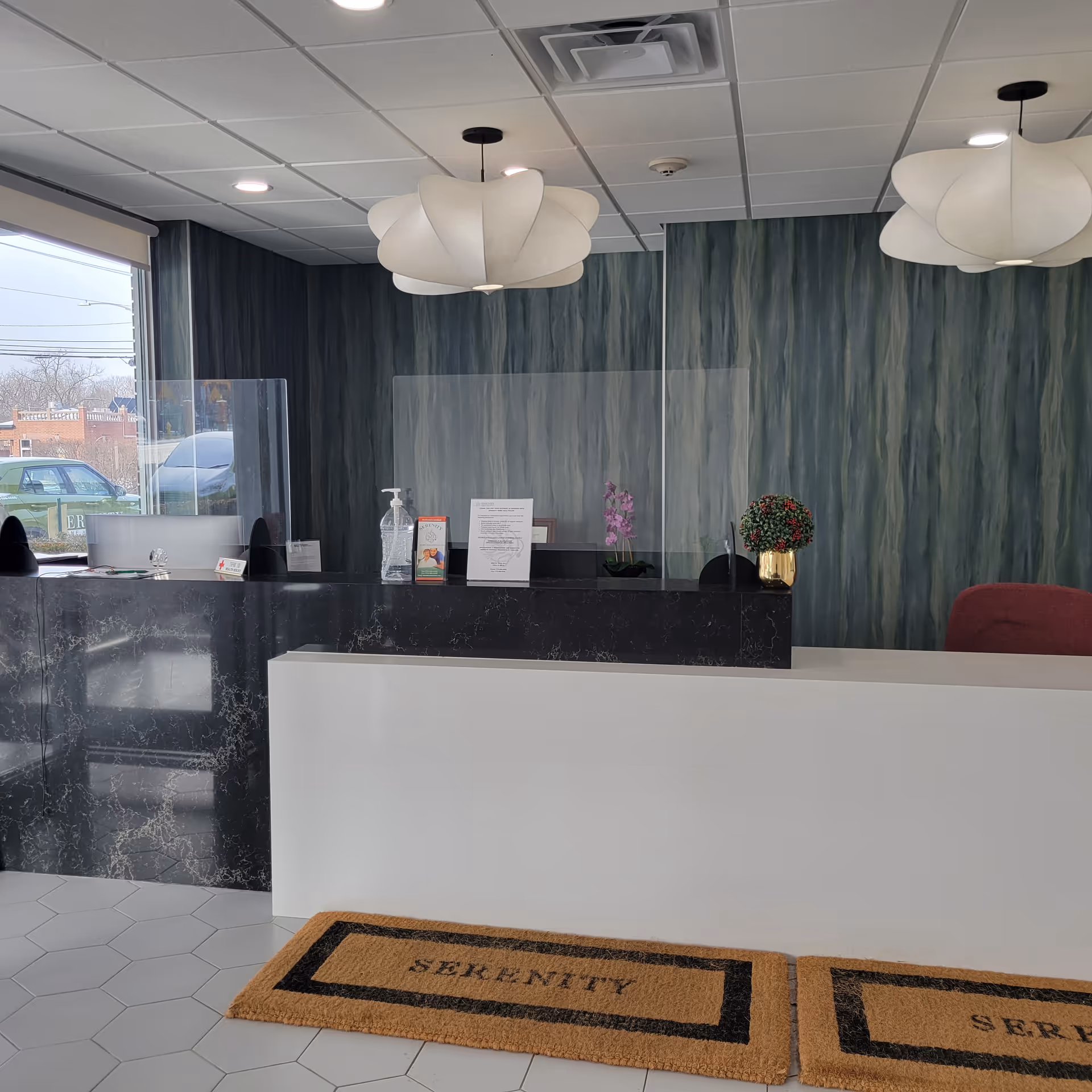 Modern lobby reception with a black marble desk and glass partitions.
