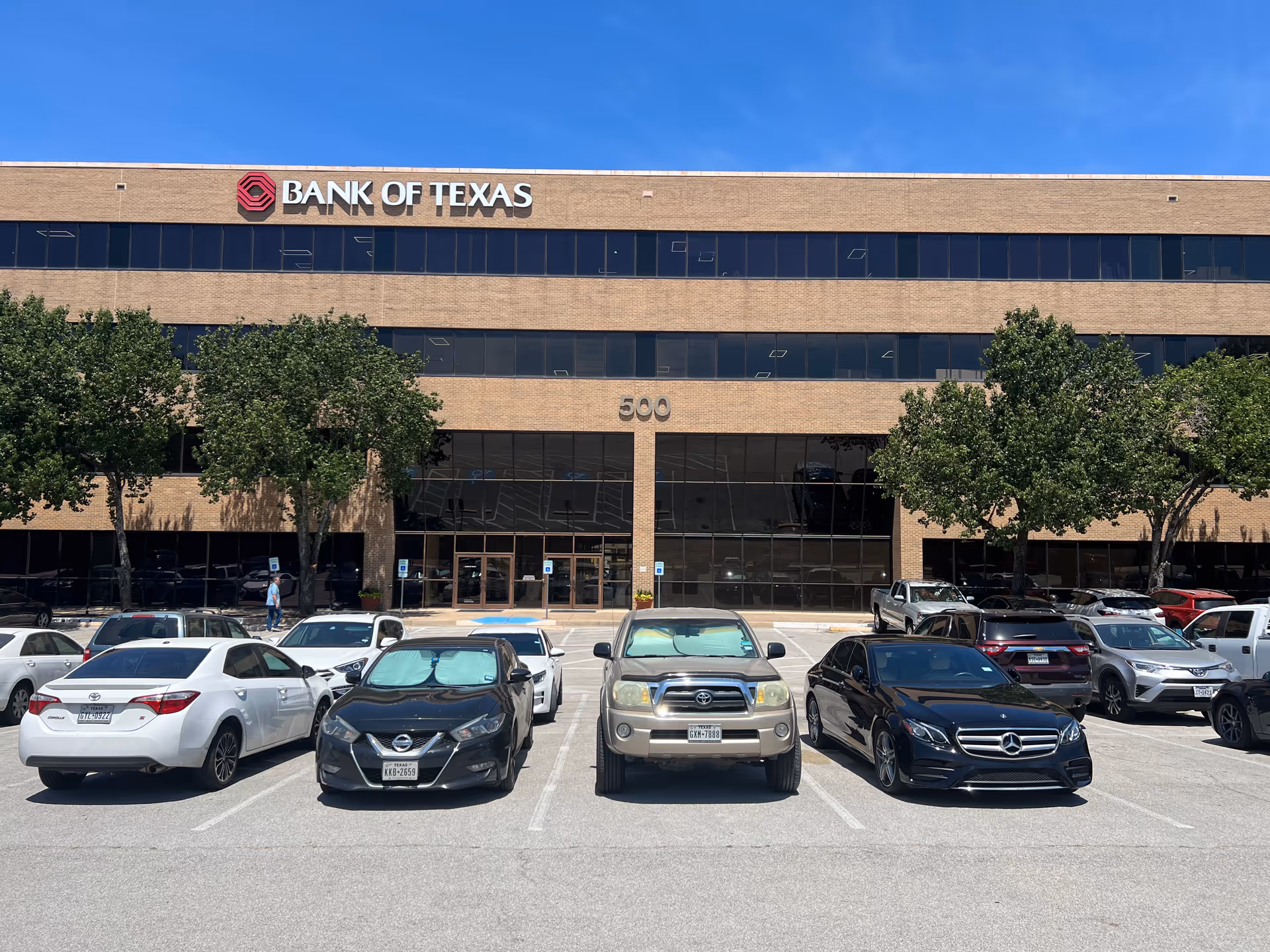 Front view of Bank of Texas building with a parking lot in foreground.