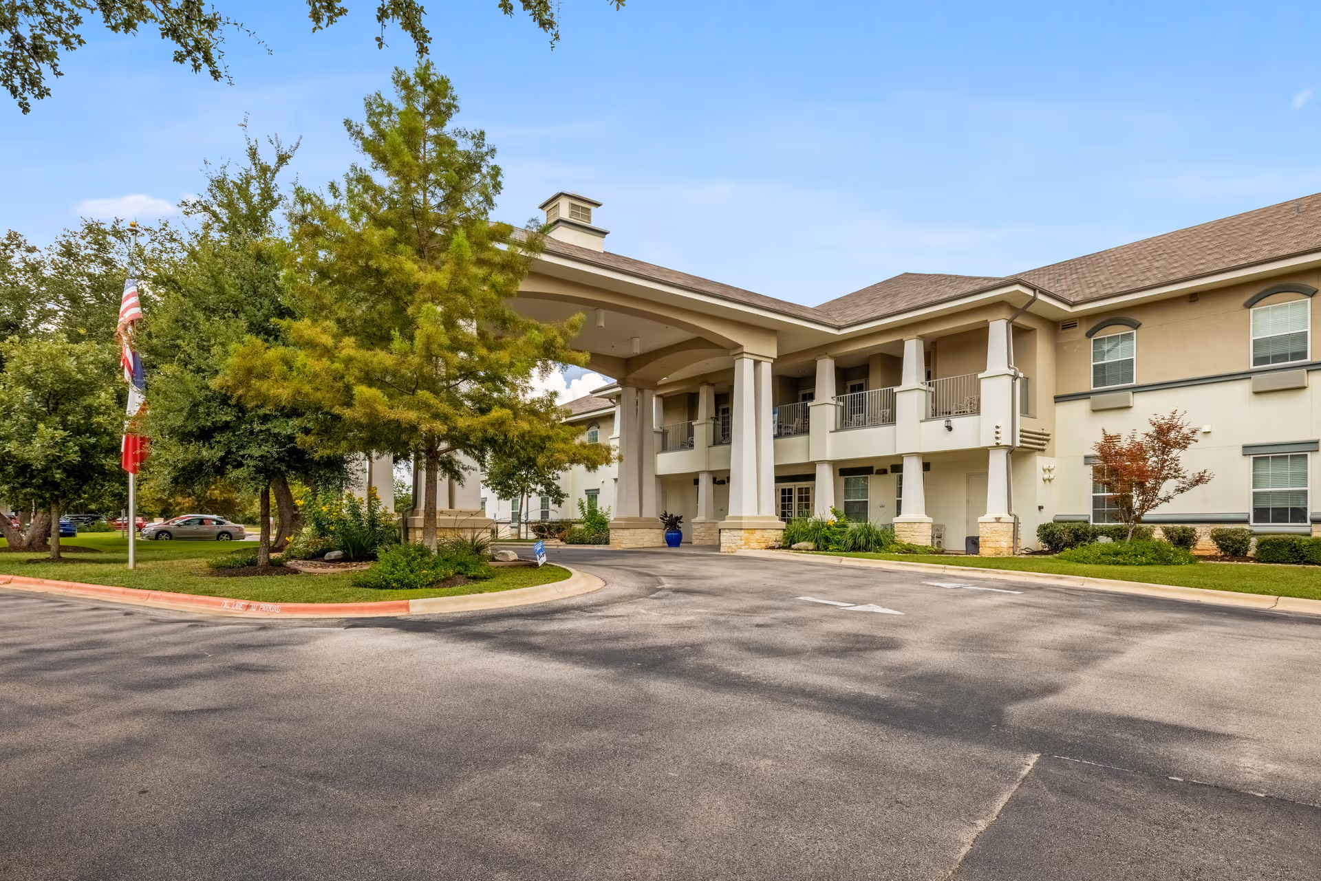 Front view of a senior living facility with porte-cochère and landscaping.
