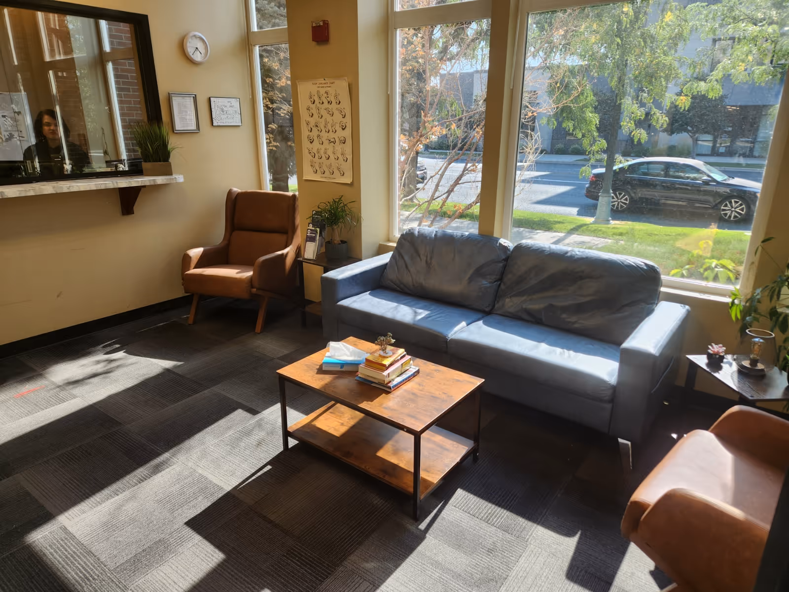 Bright lobby seating area with sofa, chairs, coffee table, plants, and large windows.