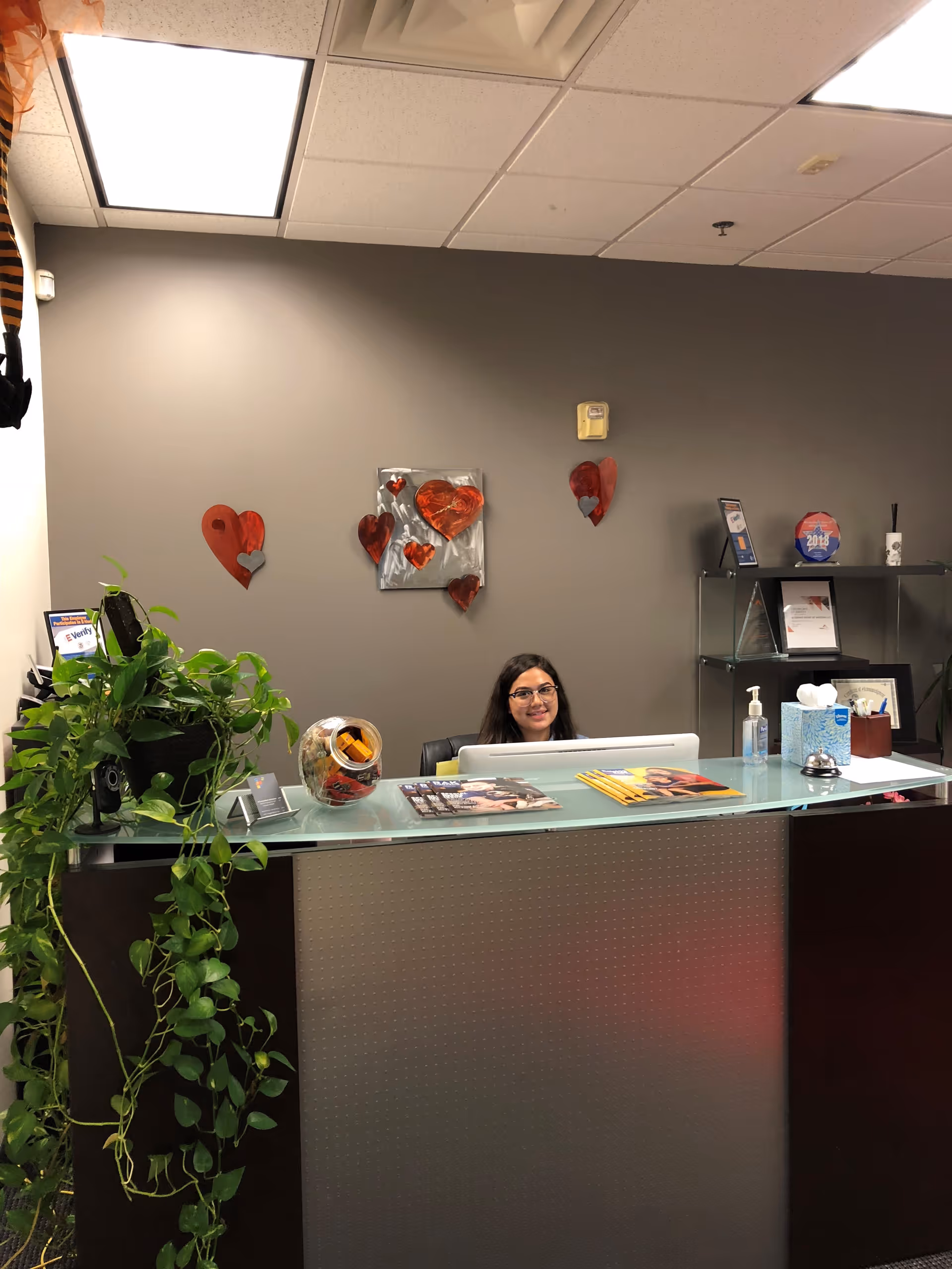 Reception desk inside a senior living facility with a staff member and heart-themed wall art