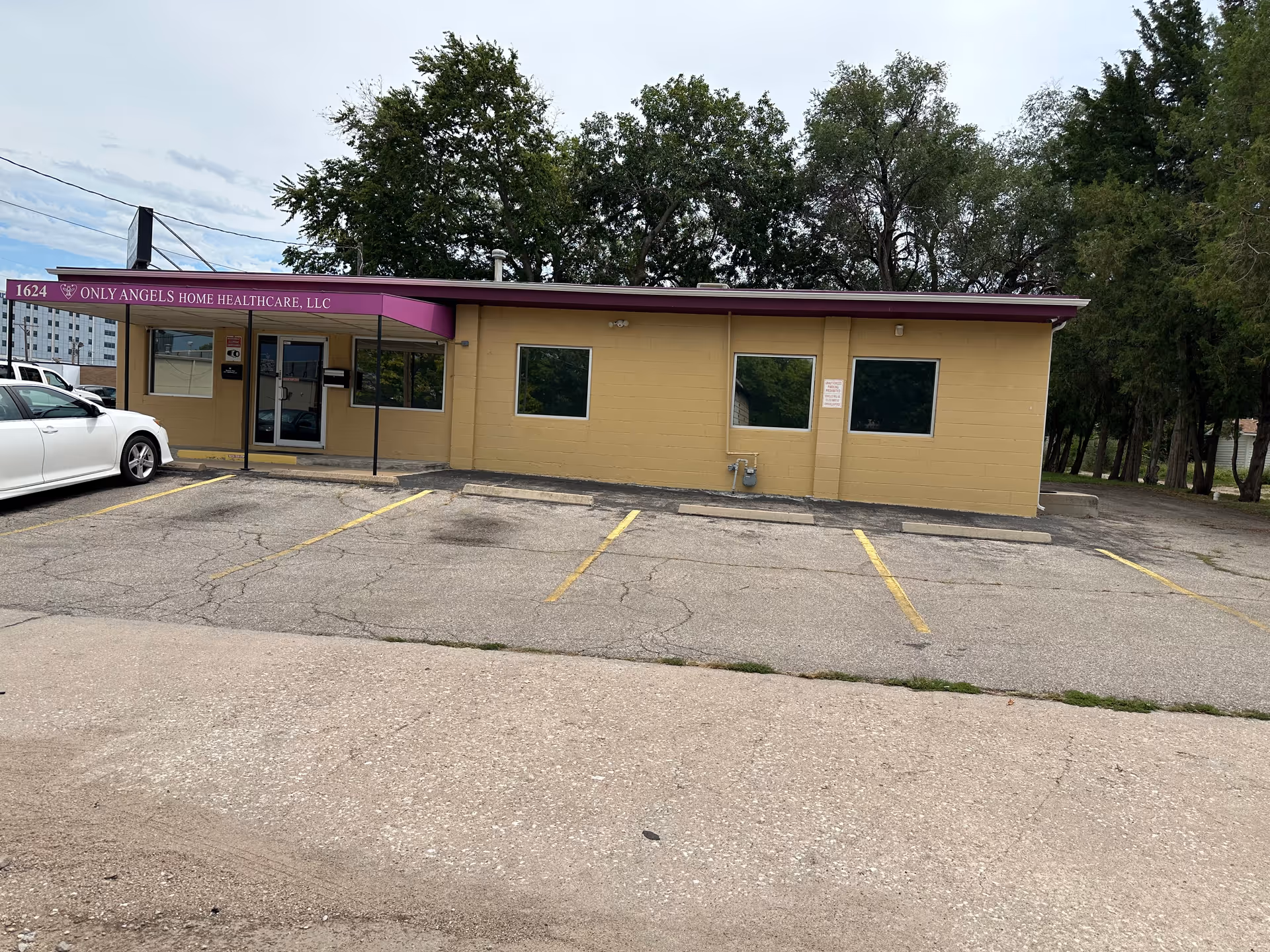 A single-story beige facility with a purple awning and a white car in the parking lot.