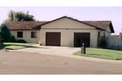 Front exterior of a beige, single-story facility with two brown garage doors and a driveway.