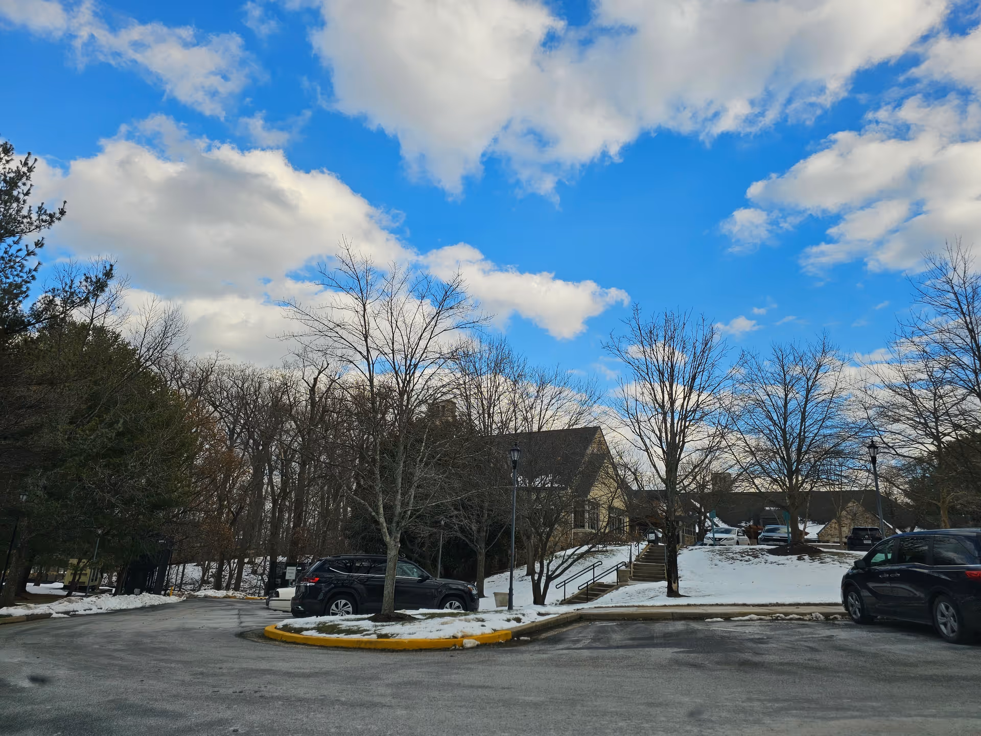 Snow-covered parking lot in front of a brown-roofed building with bare trees