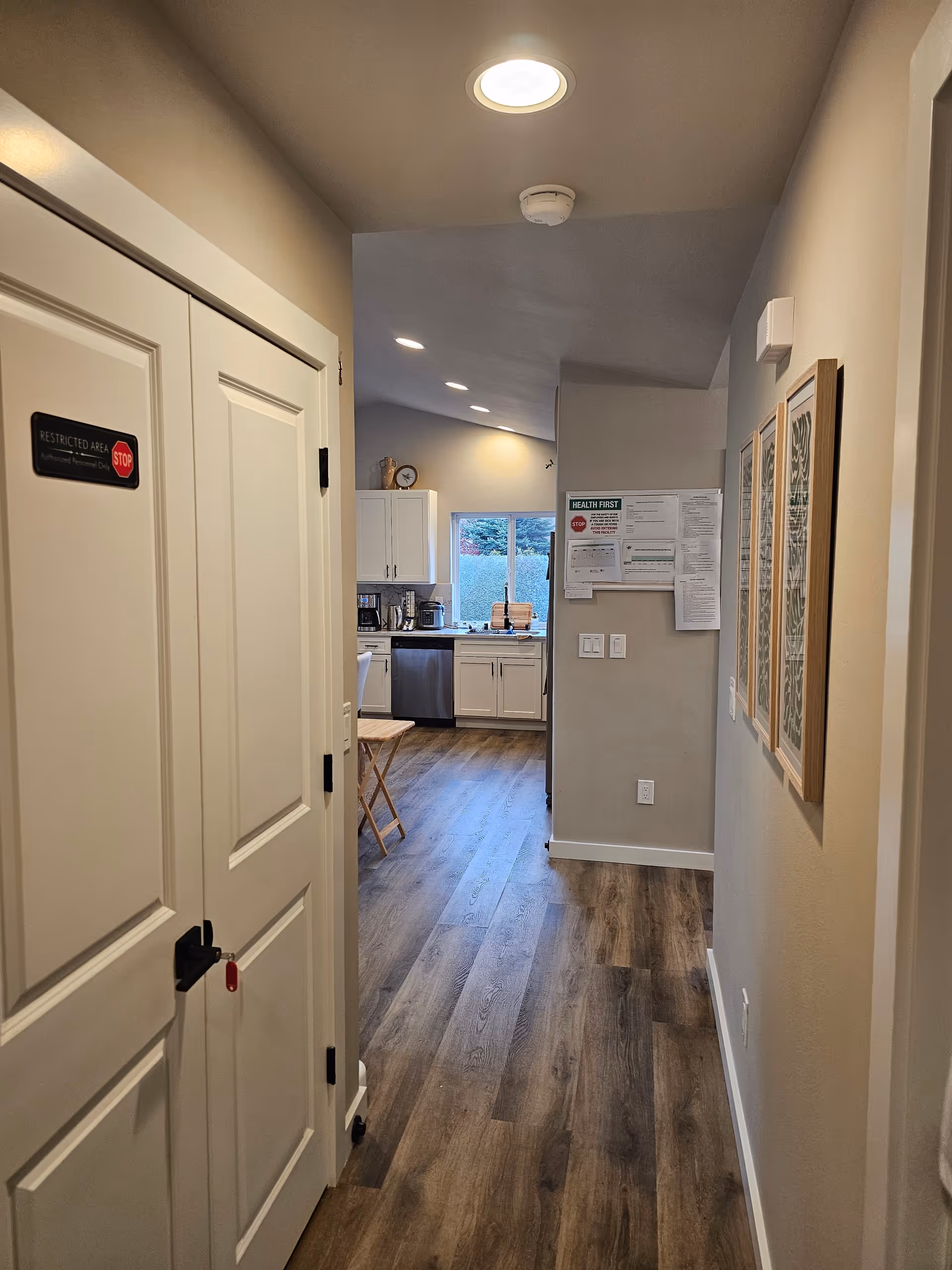 Hallway view inside a senior living facility leading to a bright kitchen.