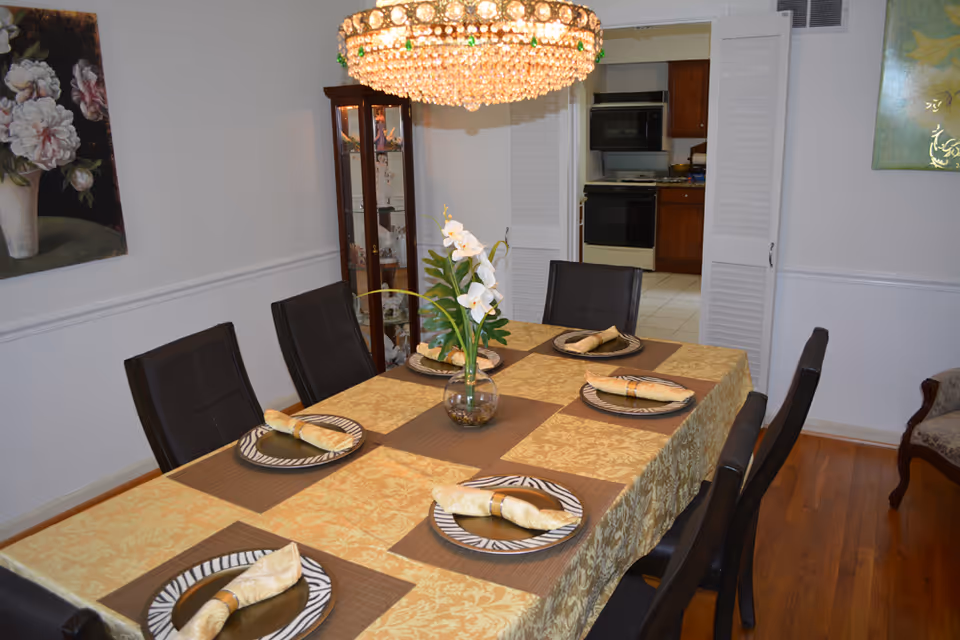 Dining room with a long table set for a meal and a chandelier.