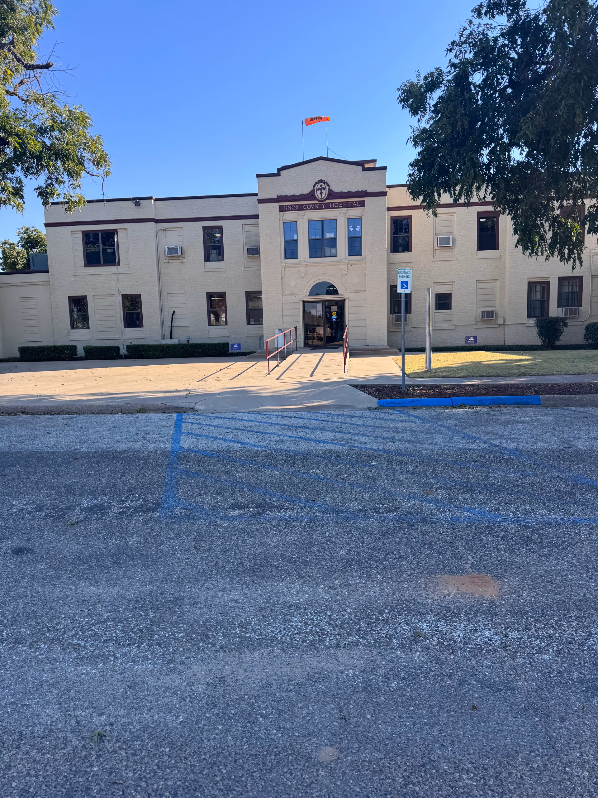 Front view of Knox County Hospital building with entrance, ramp, and parking lot.