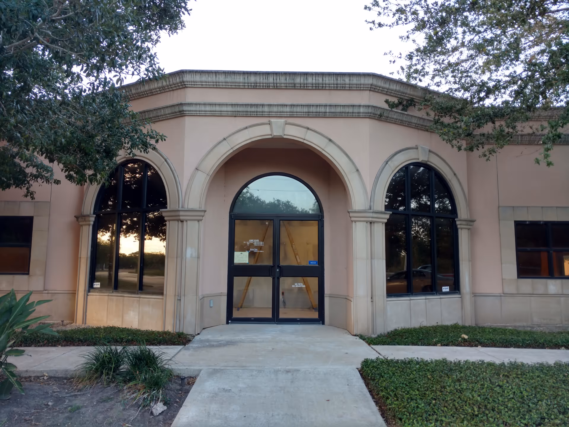 Beige building exterior with arched windows and a double-door front entrance.
