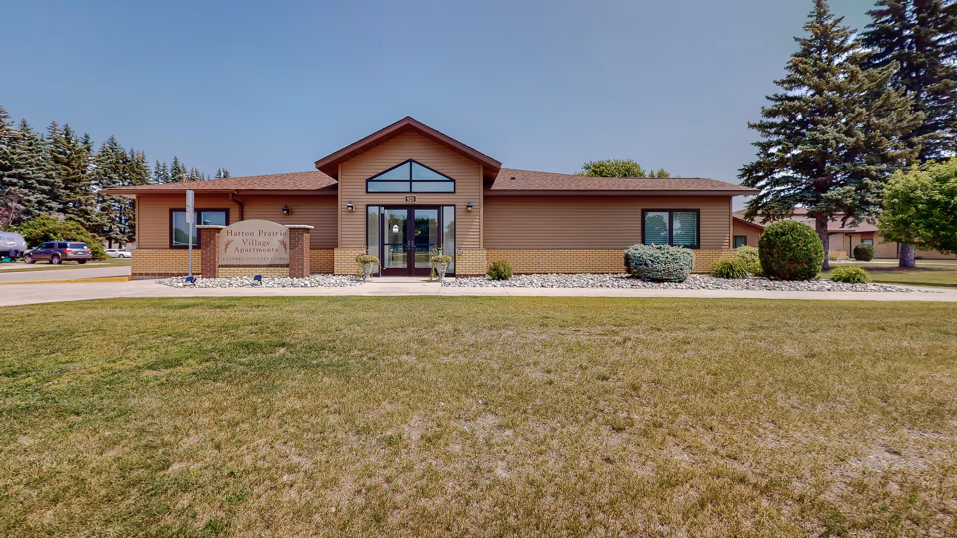 Front view of Hatton Prairie Village senior living facility with glass entrance and sign.
