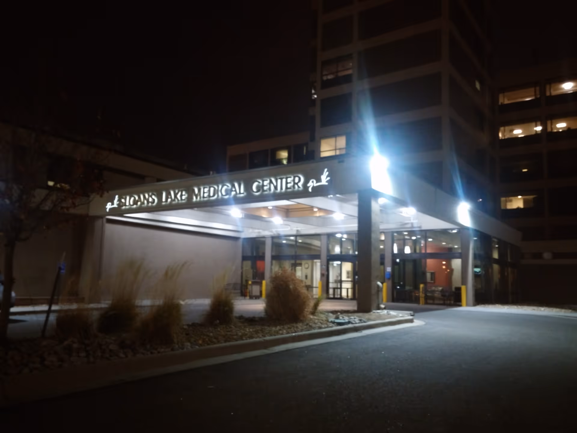 Night exterior of Sloan's Lake Medical Center entrance with glass doors.