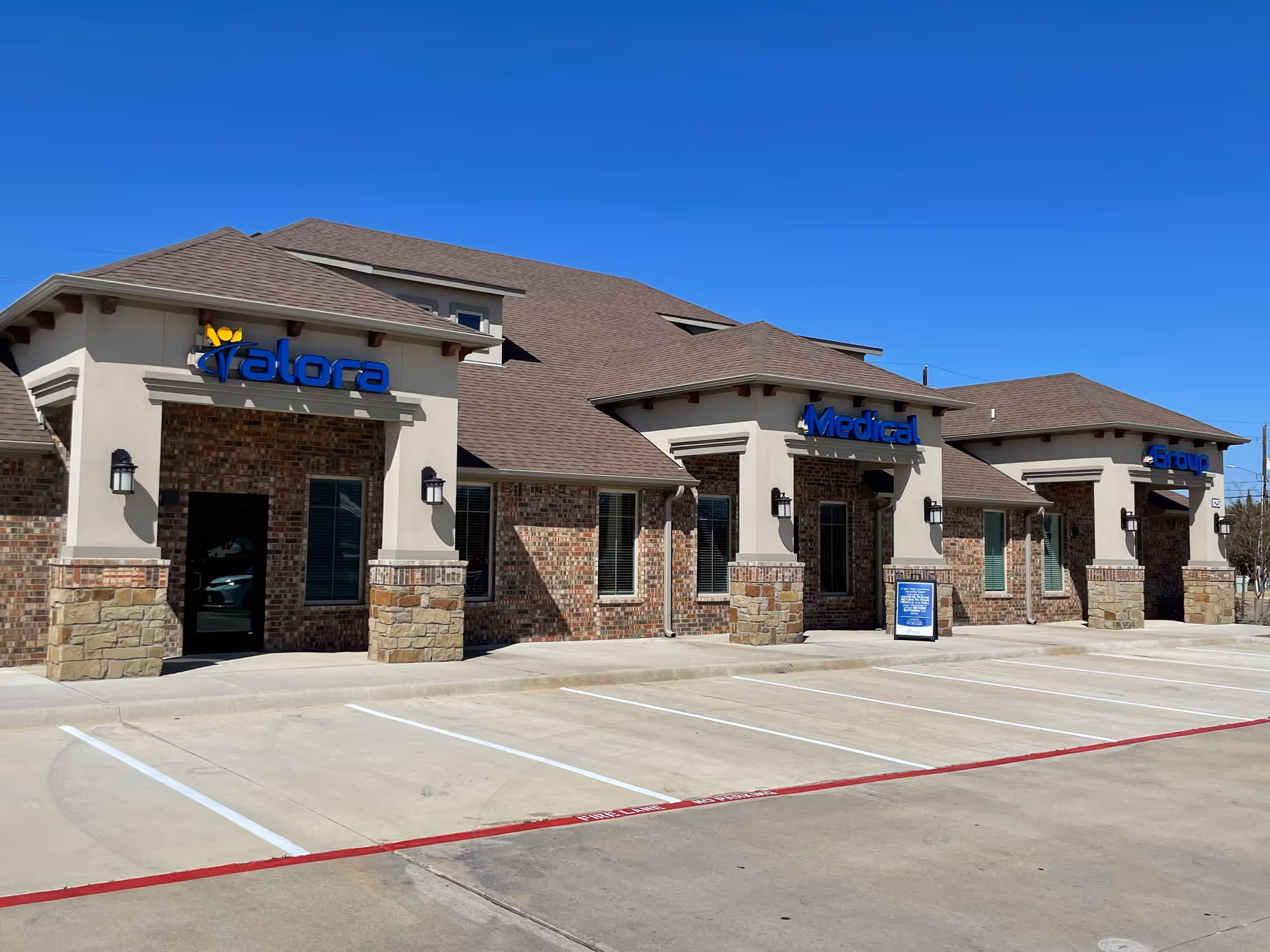 Exterior view of a Valora Medical Group clinic strip under a blue sky.