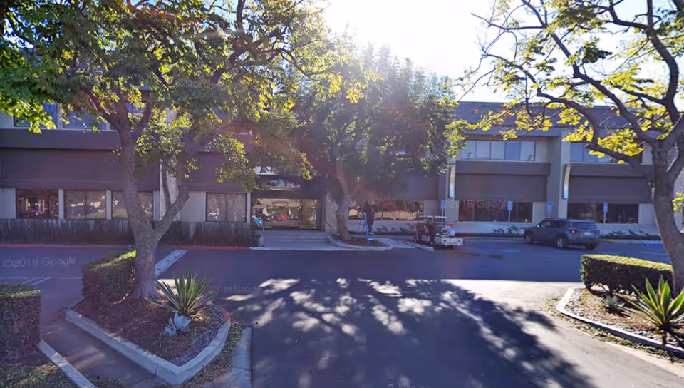 Exterior view of Rainbow Home Care Services, Inc. facility with trees, shrubs, and a front entrance.