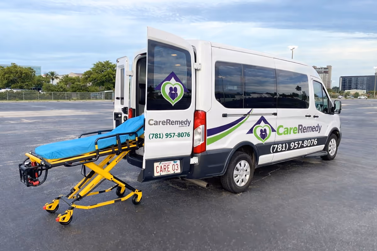 White CareRemedy van with a patient stretcher extended in a parking lot.