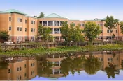 Front exterior view of Lofland Park Center, a senior living facility, with trees and a pond.