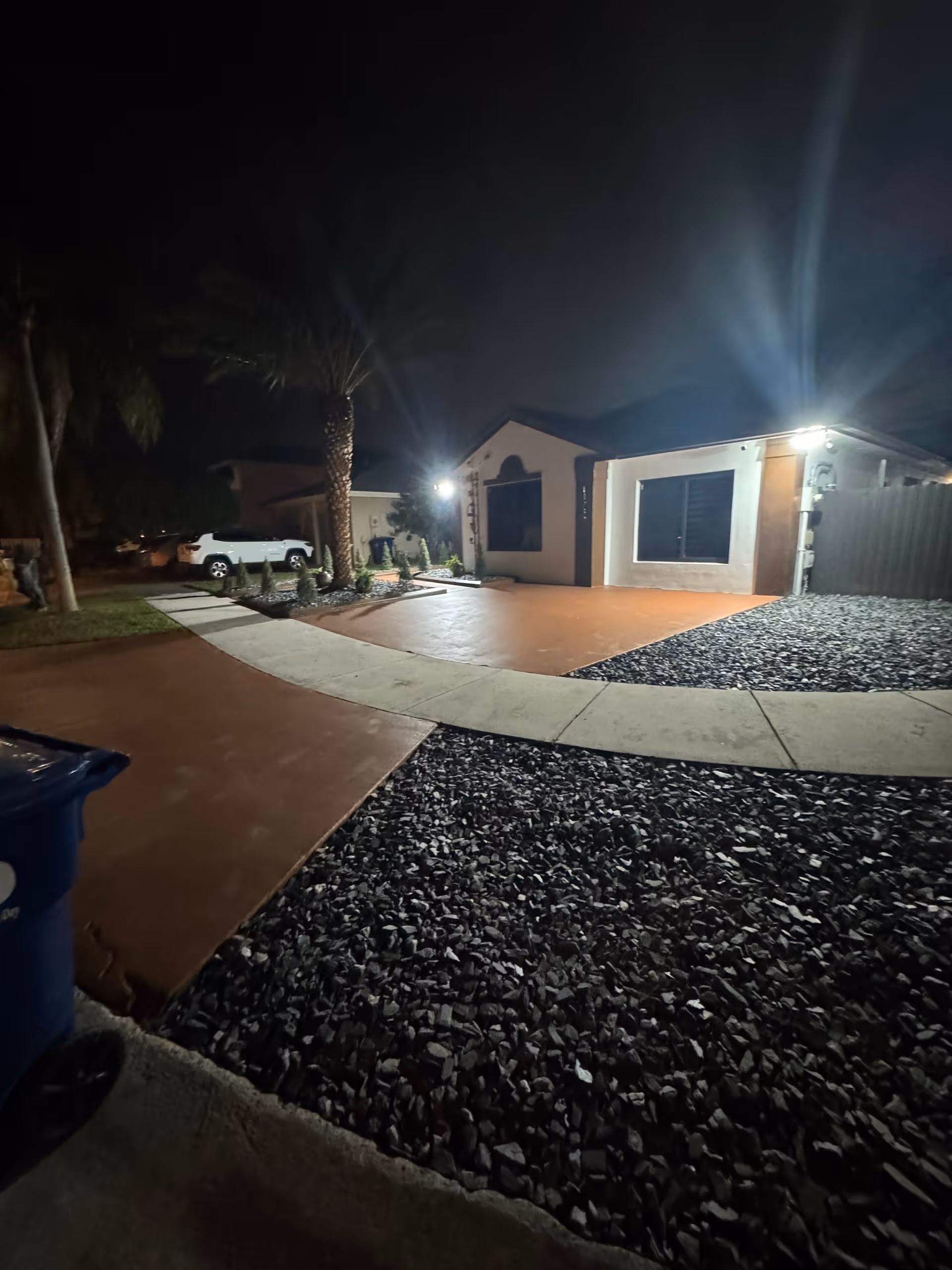 Nighttime exterior view of Cruz Family ALF No 2 with lit entrance and rocky landscaping.