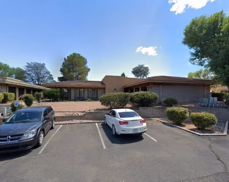 Single-story building with a parking lot and trimmed shrubs in front.