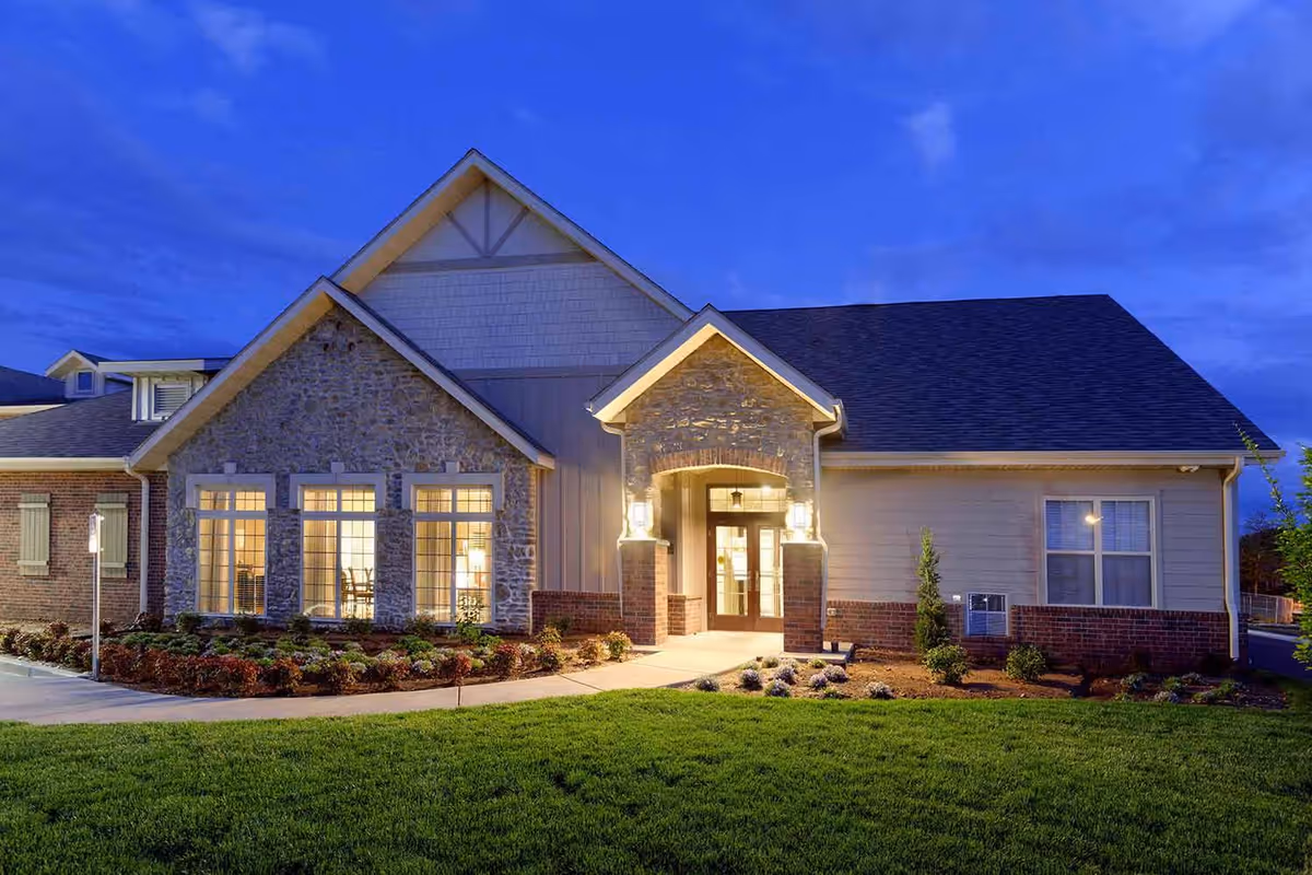 Exterior view of Castlewood Senior Living with stone facade and illuminated entrance.