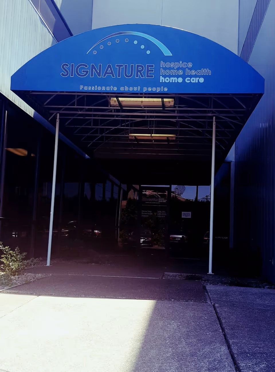 Blue canopy entrance with Signature hospice home health sign at a building front.