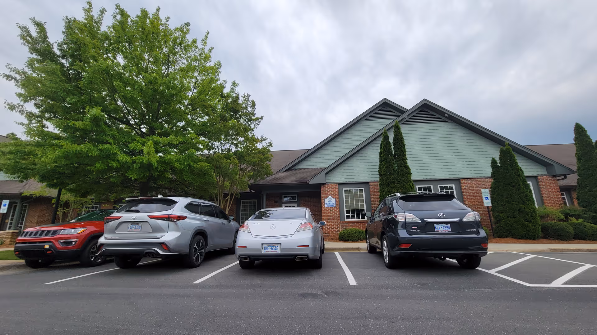 Front view of Trellis Supportive Care building with parked cars and trees.