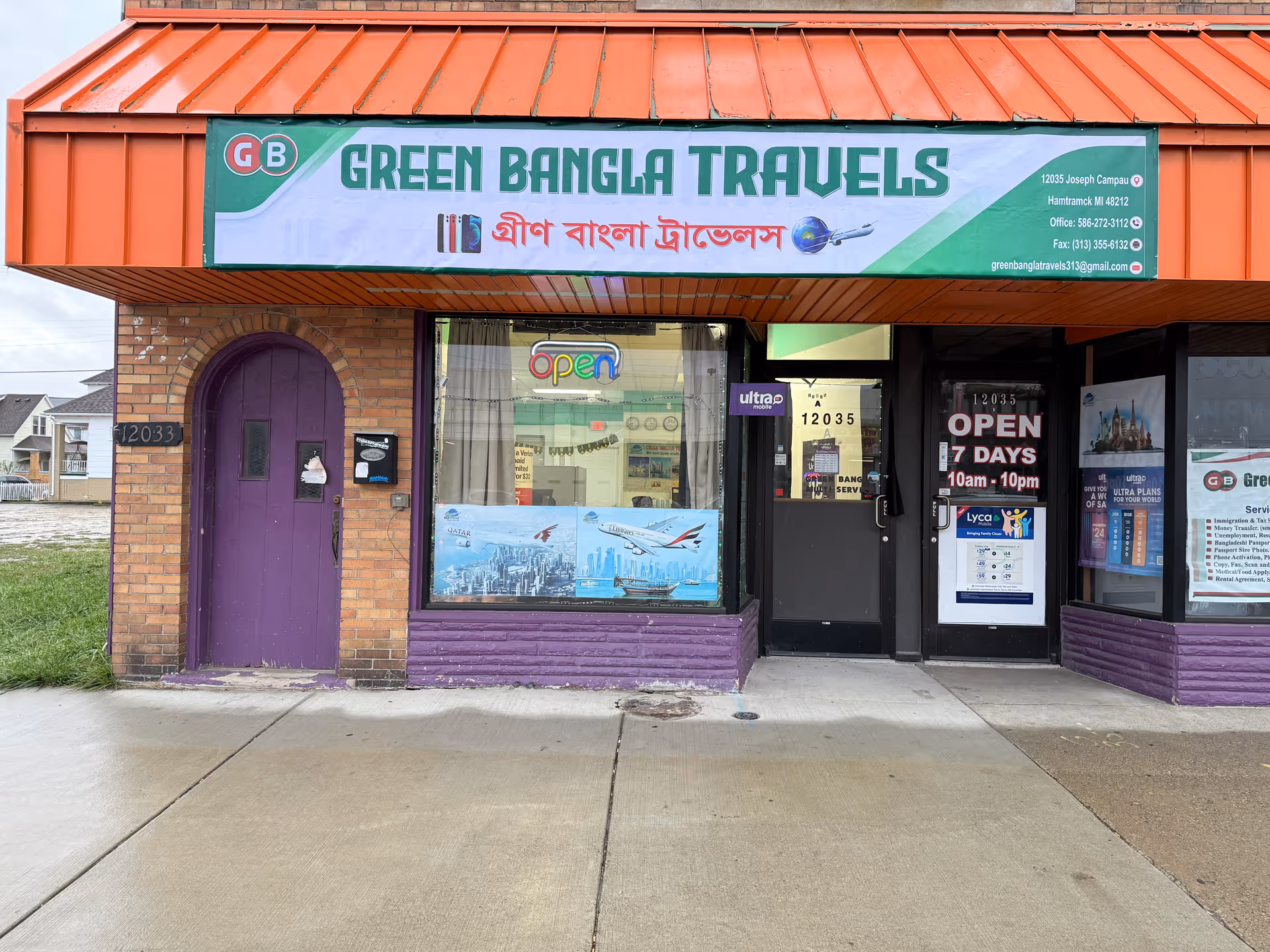 Front view of a brick building with an orange awning and Green Bangla Travels sign