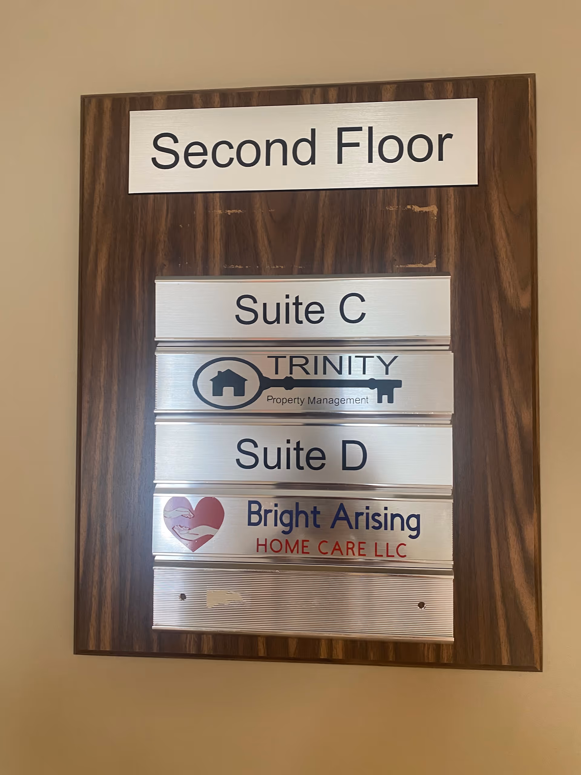 Wooden framed directory listing Second Floor, Suite C, Suite D, and Bright Arising Home Care LLC.