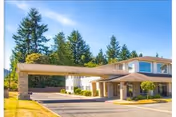 Two-story senior living facility with a covered entrance, driveway, and well-kept landscaping.